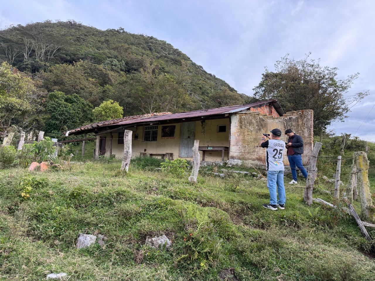 La fachada de la casa con dos personas revisando y documentando el estado de la construcción